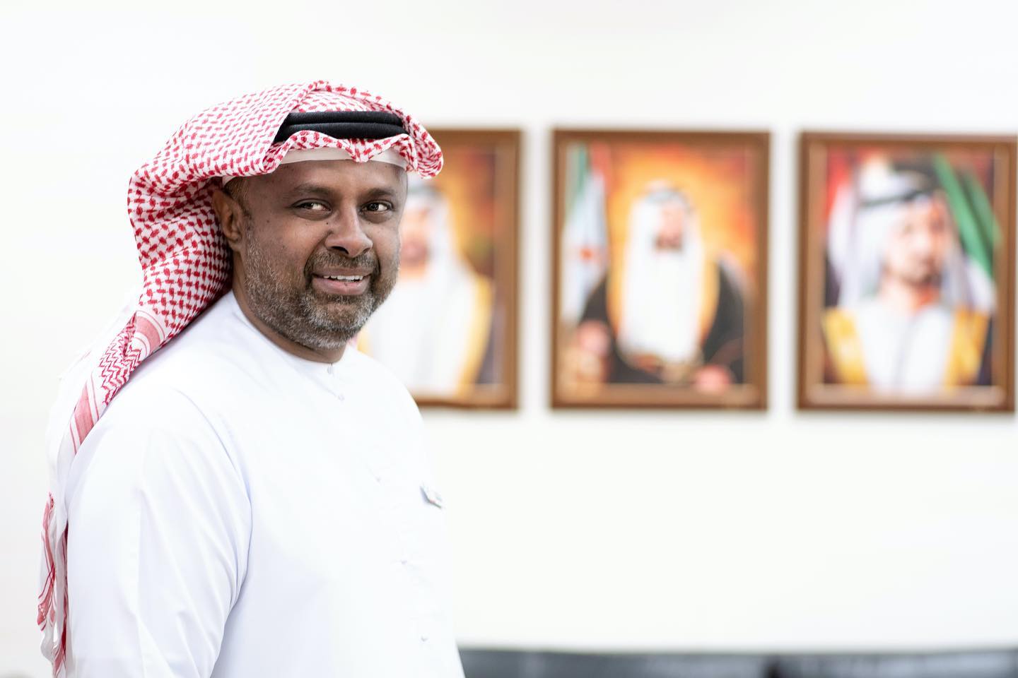 An Arab man stand behind the images of Rulers of UAE