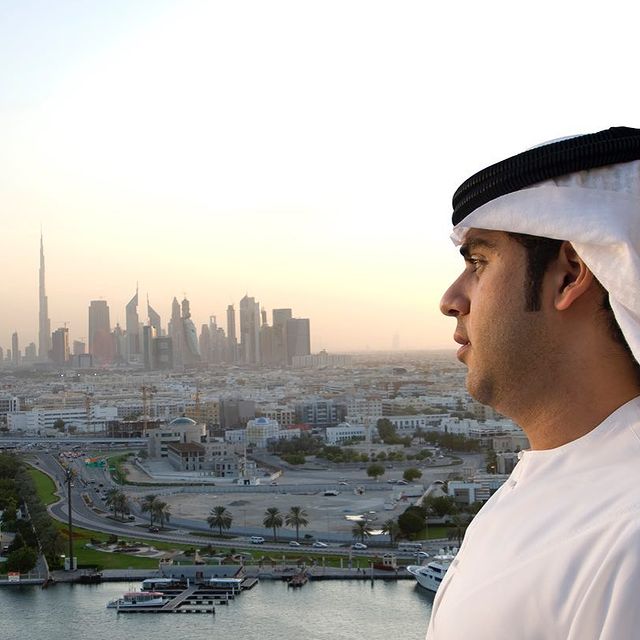 a young Arab Sheikh in an image and toward him the all buildings of Dubai can be seen